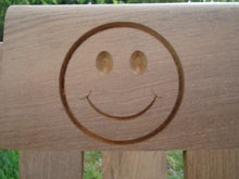 Load image into Gallery viewer, Smiley face logo carved into wood on a memorial bench - 4mb0965