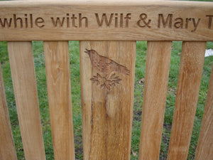 Singing bird on a branch carved into wood on a memorial bench - 4mb1505