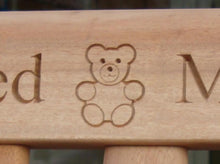 Load image into Gallery viewer, A Teddy bear symbol carved into wood on a memorial bench - 4mb2756